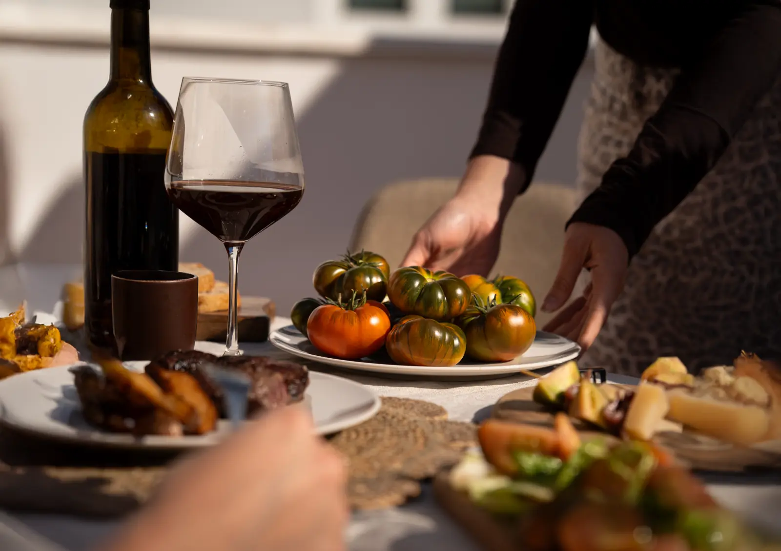 Plato de tomates RAF en una mesa compartida, con vino y aperitivos